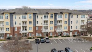 A multi-story apartment building with a parking lot in front. - 2BR/2BA Luxury | Walkable + Parking | PET Friendly (Charlotte)