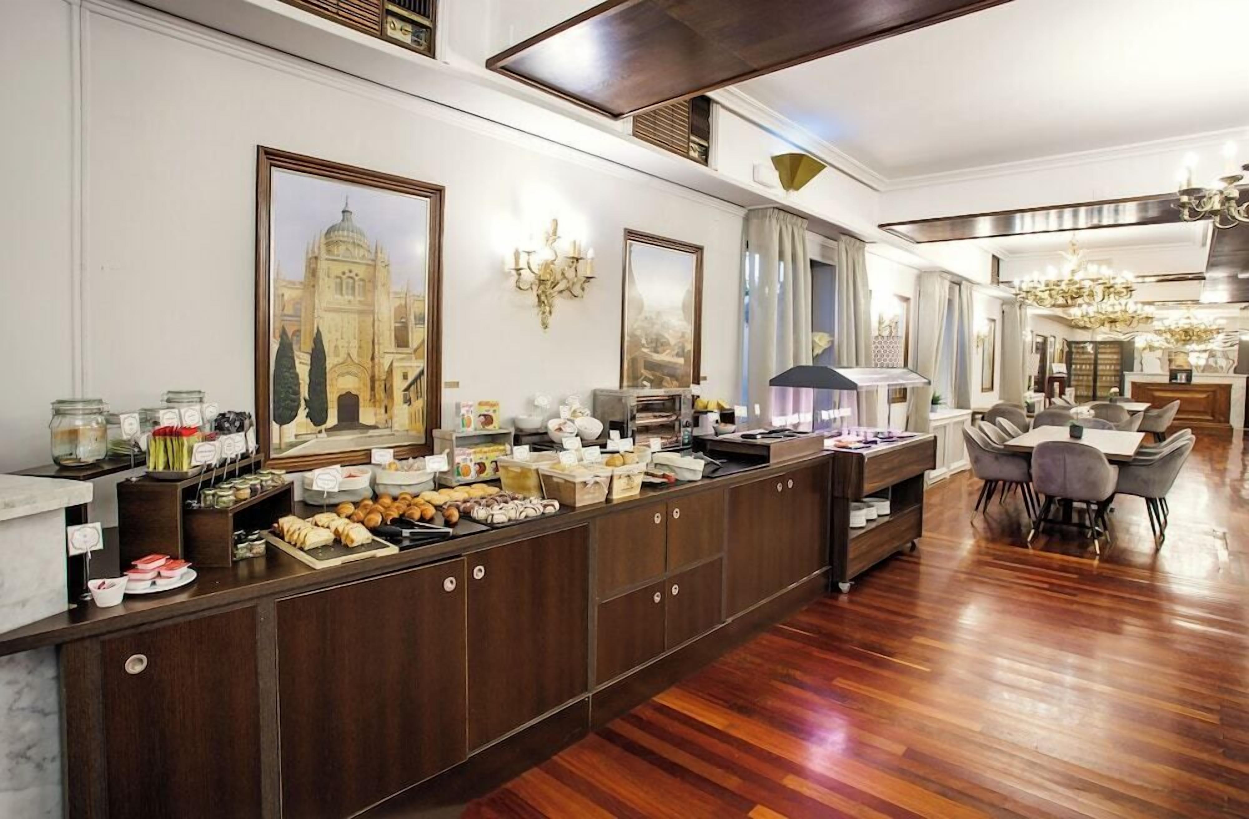Una hall d'albergo con un buffet, un lampadario e un grande dipinto raffigurante un edificio.
