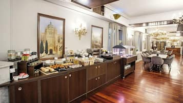 Una hall d'albergo con un buffet, un lampadario e un grande dipinto raffigurante un edificio.
