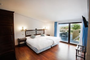 A bedroom with a large bed, a wooden wardrobe, a nightstand, and a view of the outdoors through a sliding glass door. - Conde Rodrigo II (Ciudad Rodrigo)