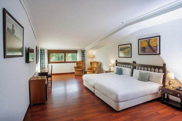 A hotel room with a large bed, a desk, two chairs, and artwork on the walls. - Conde Rodrigo II (Ciudad Rodrigo)