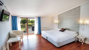 A bedroom with a bed, a chair, a desk, a TV, and a balcony with curtains.