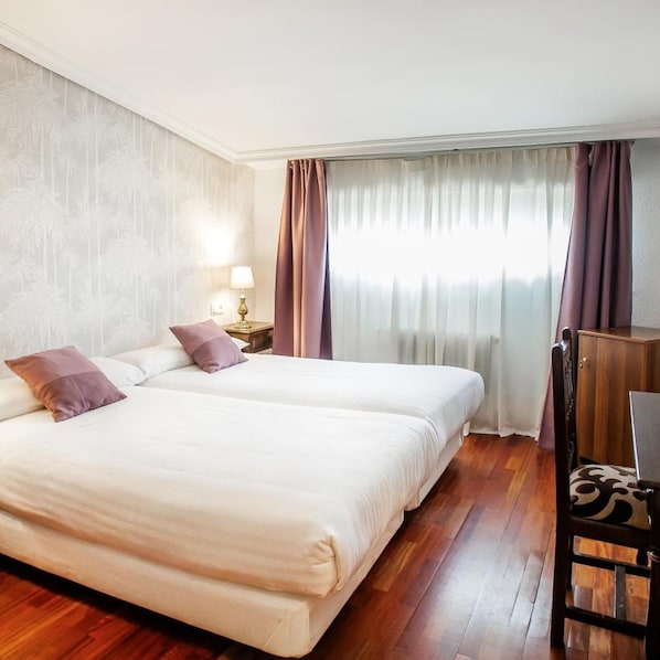 A double bed with two pillows, a nightstand with a lamp, a wooden chair, and a window with curtains. - Conde Rodrigo II (Ciudad Rodrigo)