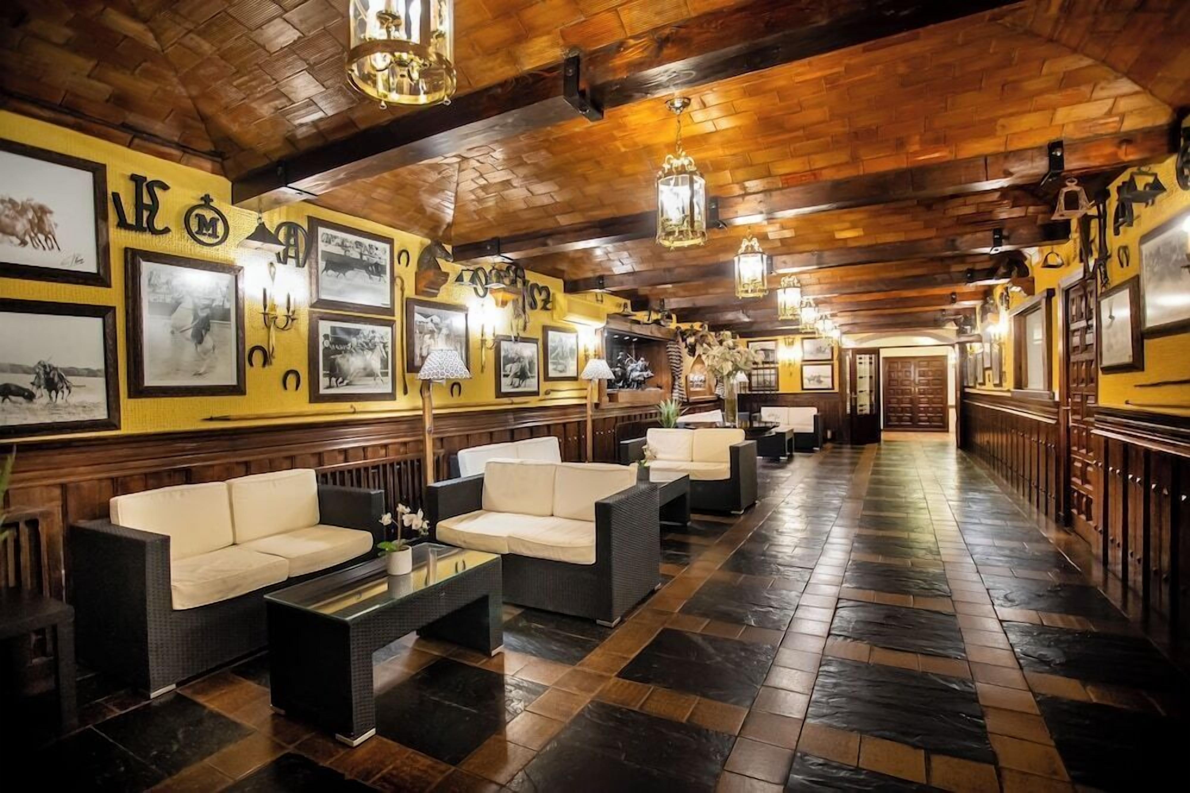 A hotel lobby with a wooden ceiling, framed pictures on the walls, and a seating area with sofas and a coffee table.