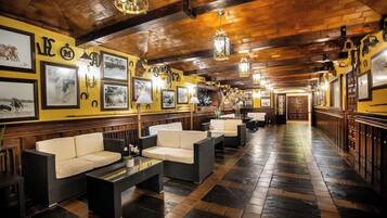 A hotel lobby with a wooden ceiling, framed pictures on the walls, and a seating area with sofas and a coffee table.