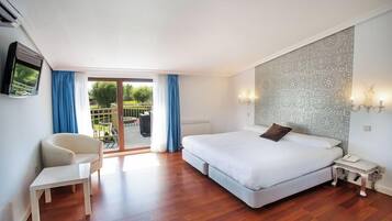 A hotel room with a bed, a chair, a small table, a wall-mounted TV, and a view of the outdoors.