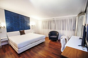 Una habitación de hotel con una cama grande, un escritorio, una silla y un televisor.