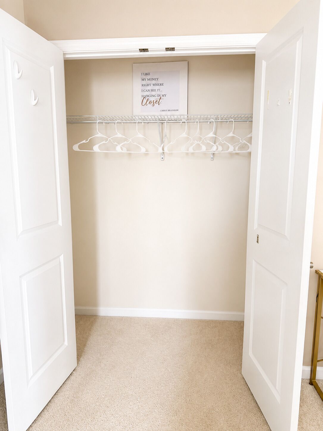 A walk-in closet with a hanging rod and a sign on the wall.