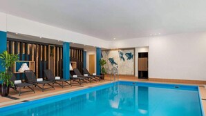 Una piscina con sillones de descanso y una pared decorada con motivos de peces.