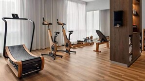 Una sala de estar moderna con una caminadora, bicicletas estáticas y un mueble de entretenimiento de madera.
