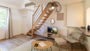 A modern living room with a wooden staircase, a television, a dining area, and a kitchen. - Perchoir d'Augustin Arras • calme • CLIM • centre (Arras)