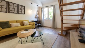 Ein Wohnzimmer mit Sofa, Couchtisch, Schreibtisch und einer Treppe.