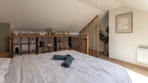 Una camera da letto con un letto, scaffali in legno, una scala e un quadro appeso al muro.