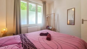 A bedroom with a bed, a window, a mirror, and a bedside table. - Rez-de-chaussée de la Mairie • CLIM • terrasse (Arras)