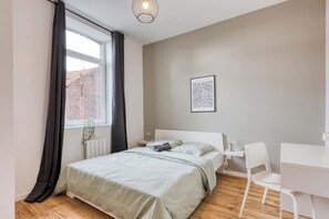 A bedroom with a bed, a desk, and a chair.
