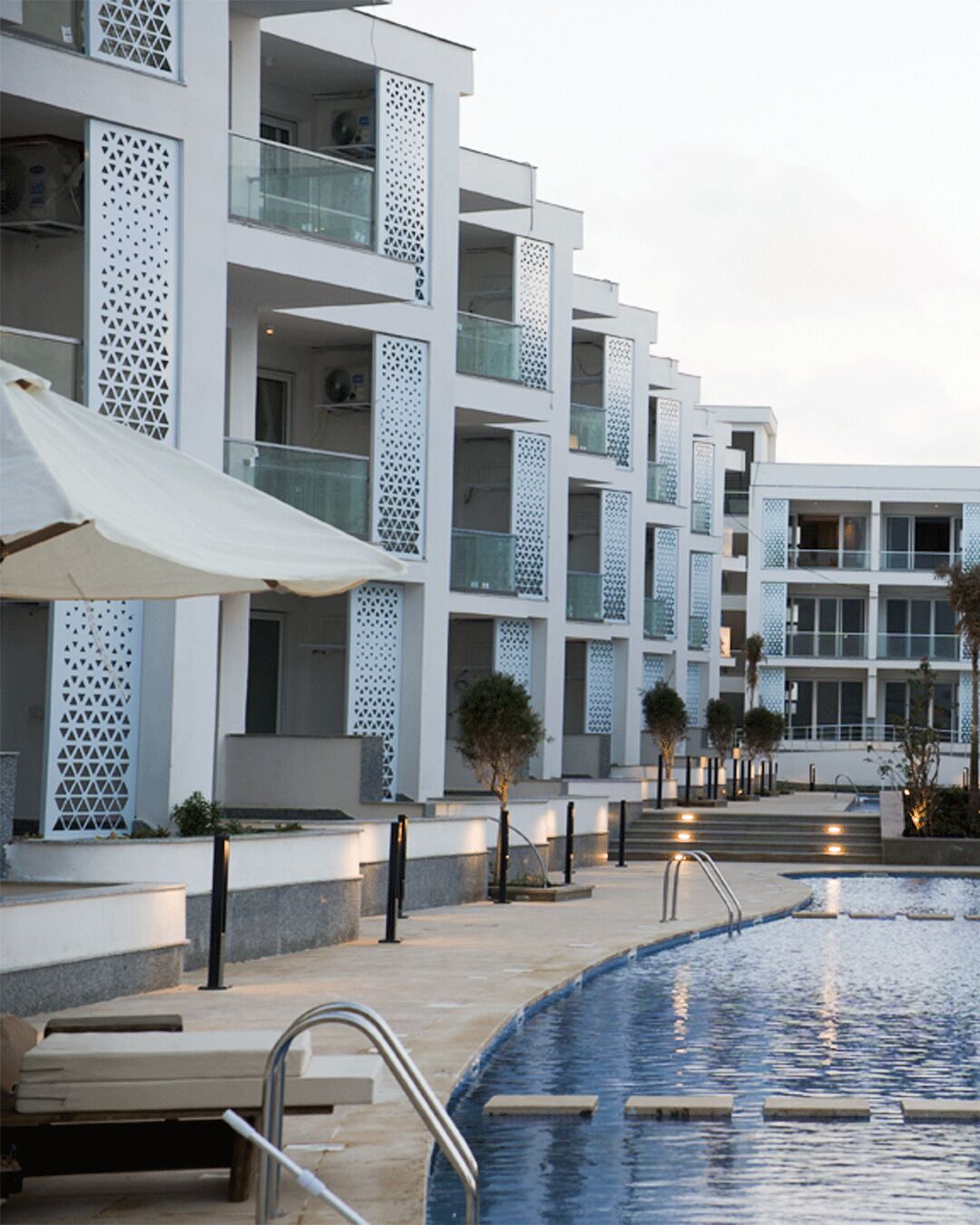 Un hôtel moderne doté de nombreux balcons, d’une piscine et d’espaces de détente en plein air.