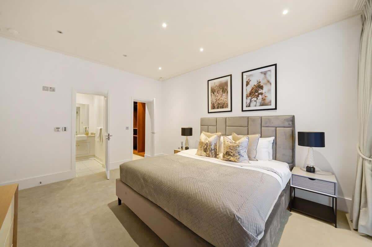 Une chambre à coucher avec un lit, des tables de chevet, une tête de lit et deux tableaux encadrés au mur.