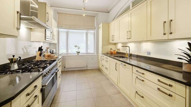 A kitchen with stainless steel appliances, beige cabinetry, and a window with a view. - HS1 - Stylish 3-Bed near Kensington High Street (Greater London)