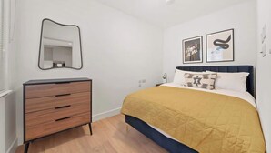 Ein Schlafzimmer mit einem Bett, einer Kommode, einem Spiegel und zwei Wandbildern.