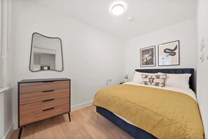 Ein Schlafzimmer mit einem Bett, einer Kommode, einem Spiegel und zwei Wandbildern.