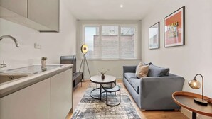 Eine moderne Küche mit integrierter Kochinsel, einem grauen Sofa und einem runden Couchtisch.