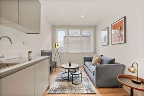 Eine moderne Küche mit integrierter Kochinsel, einem grauen Sofa und einem runden Couchtisch.