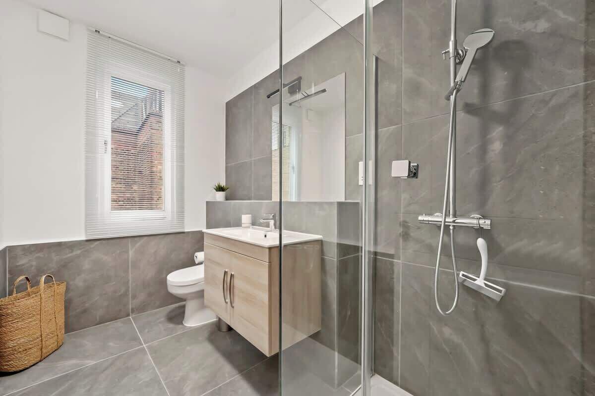 Ein modernes Badezimmer mit Duschkabine aus Glas, Toilette und Waschtisch.