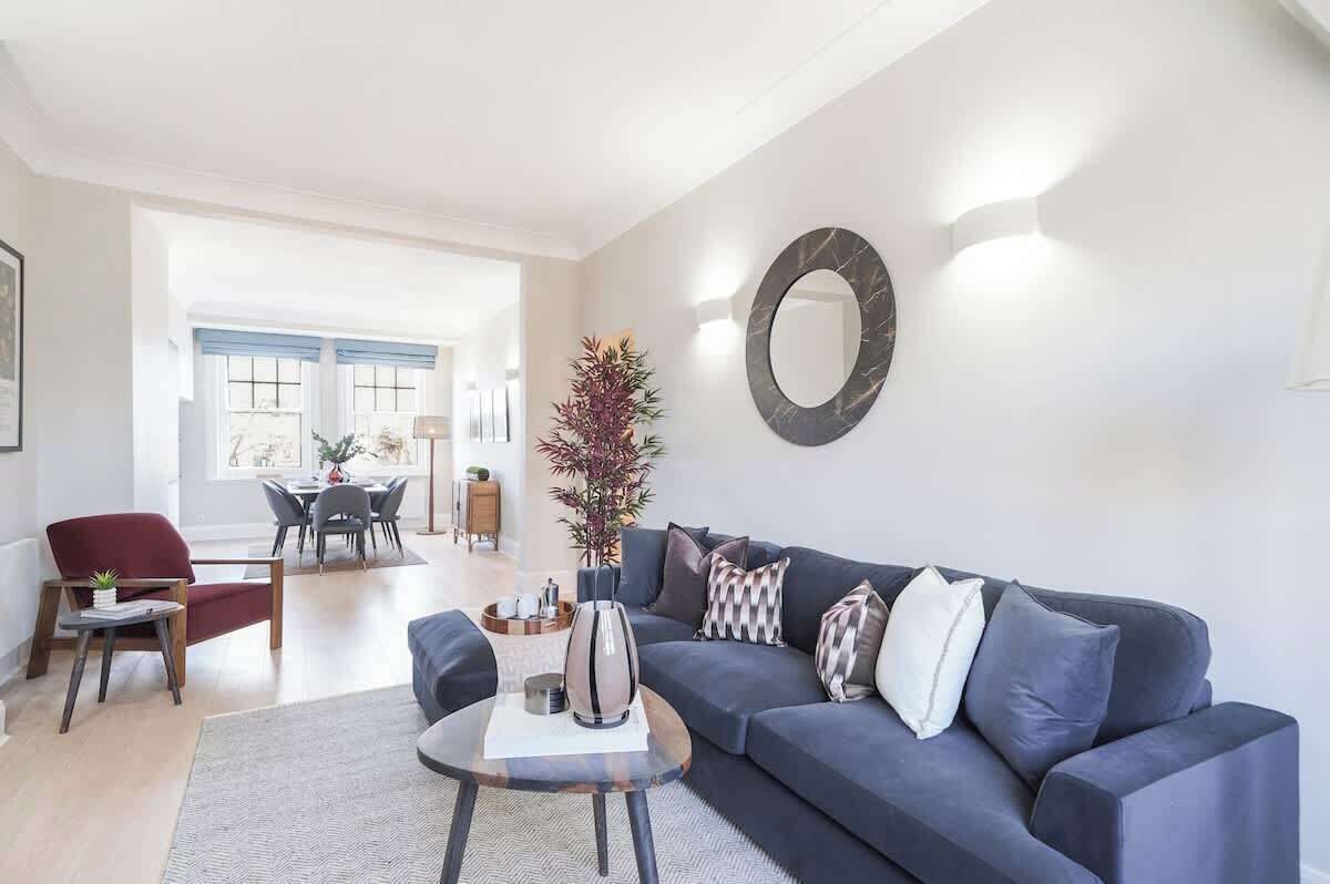A living room with a sofa, coffee table, and a dining area in the background.