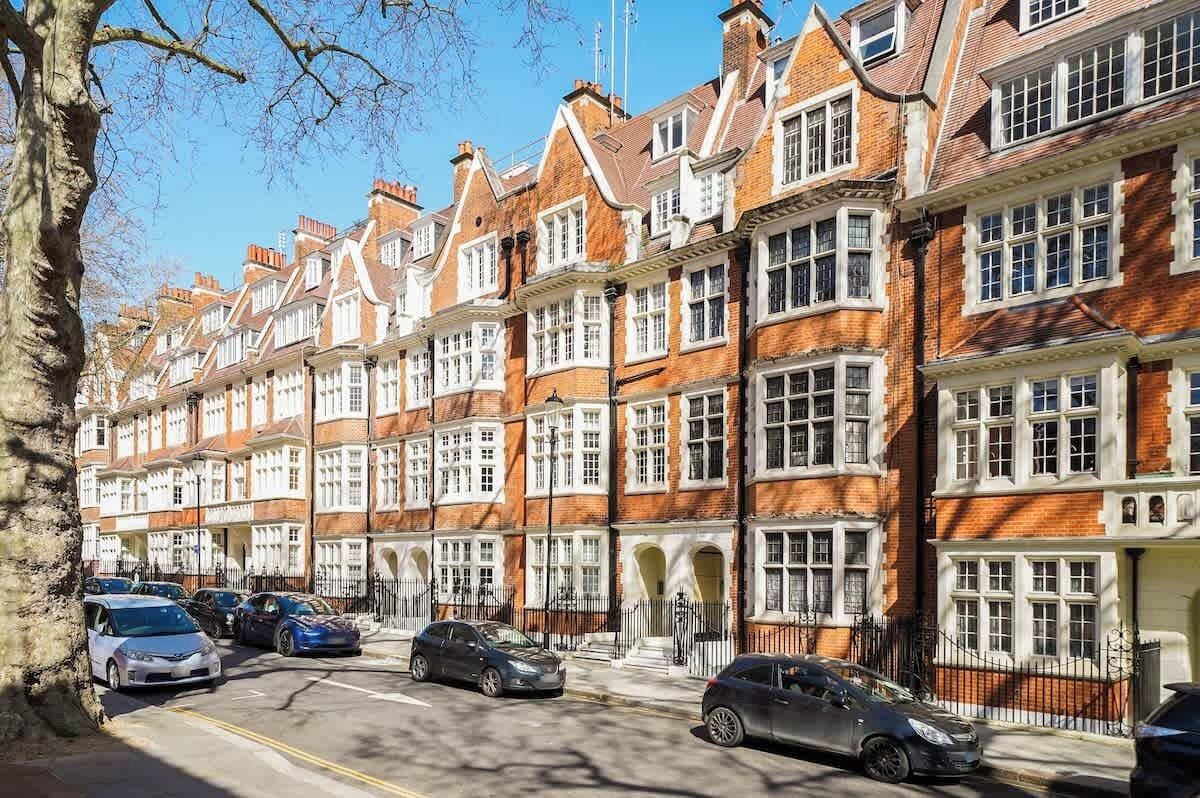 Een rij herenhuisjes van rode baksteen met witte raamkozijnen en meerdere verdiepingen.