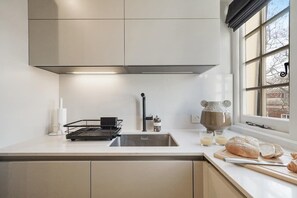 A modern kitchen with a stainless steel sink, a kettle, and a window with a view. - HS4 - Beautiful 2-Bed Family Apt in Kensington (Greater London)