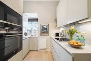A modern kitchen with a Siemens oven, a window, a radiator, and a framed picture on the wall. - HS4 - Beautiful 2-Bed Family Apt in Kensington (Greater London)
