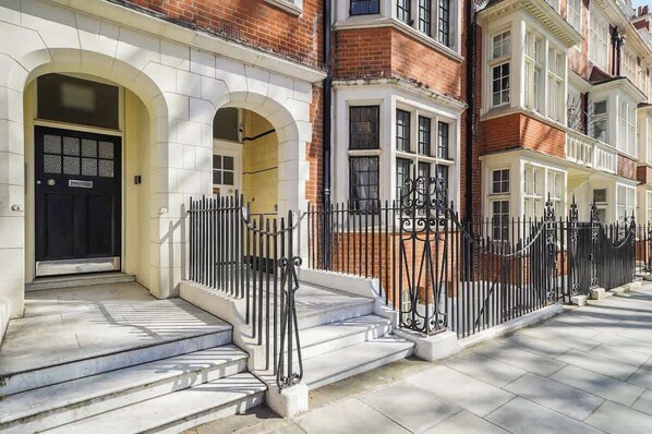 A row of terraced houses with white brick facades, black doors, and black wrought iron railings. - HS4 - Beautiful 2-Bed Family Apt in Kensington (Greater London)