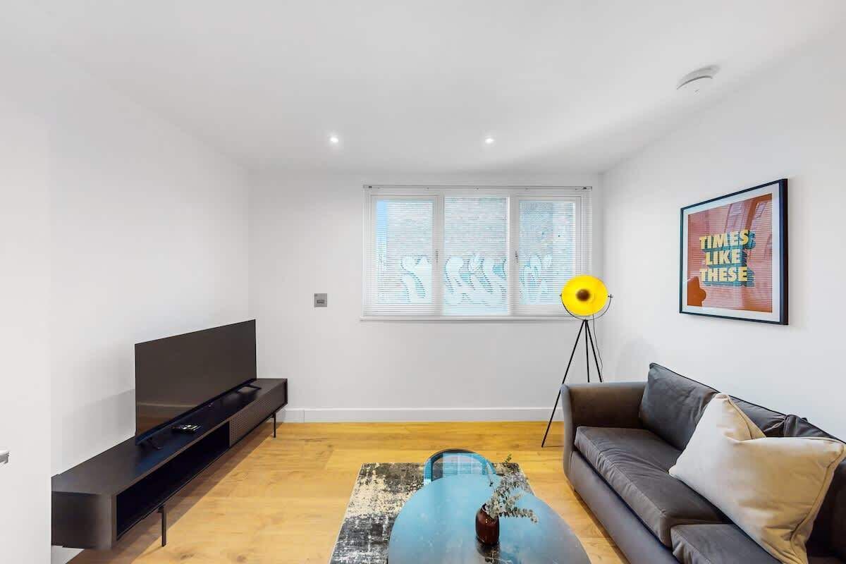 A modern living room with a flat-screen TV, a sofa, a coffee table, and a floor lamp.