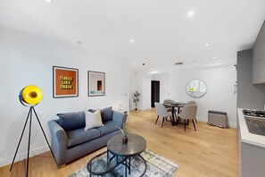 A modern living room with a sofa, coffee table, and dining area. - DA1 - Modern & Comfy 1-Bed Boutique Apartment (Greater London)