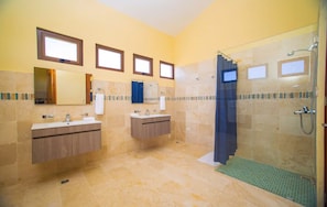 Un bagno con due lavandini, una doccia e uno specchio grande.