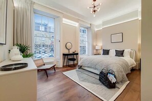 Ein Schlafzimmer mit Bett, Nachttisch, Stuhl und Blick ins Freie.