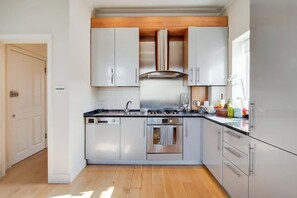 Eine moderne Küche mit Edelstahlgeräten, weißen Schränken und einer Holzbalkendecke.