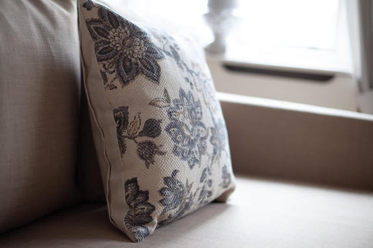 A pillow with a floral pattern on a beige sofa.