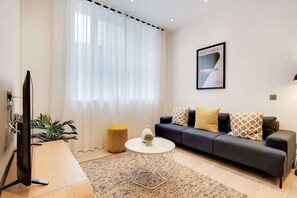 A modern living room with a sofa, a coffee table, a TV, and a plant. - BR9 - Elegant 2-Bed near Borough Market (Greater London)