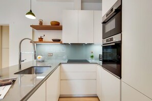 A modern kitchen with a stainless steel sink, a built-in oven, and a hanging light fixture. - BR9 - Elegant 2-Bed near Borough Market (Greater London)