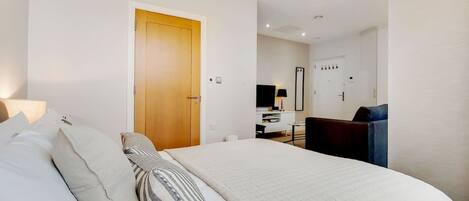 Une chambre d’hôtel avec un lit, un bureau, une chaise et un miroir.
