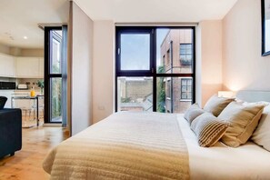 Ein modernes Schlafzimmer mit einem großen Bett, einem Schreibtisch und Blick auf die Stadt.