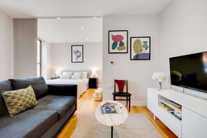 Ein modernes Wohnzimmer mit einer Couch, einem Couchtisch, einem Fernseher und Kunstwerken an der Wand.
