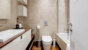 Ein modernes Badezimmer mit Waschbecken, Toilette und Dusche in Weiß.