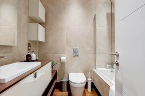 Ein modernes Badezimmer mit Waschbecken, Toilette und Dusche in Weiß.