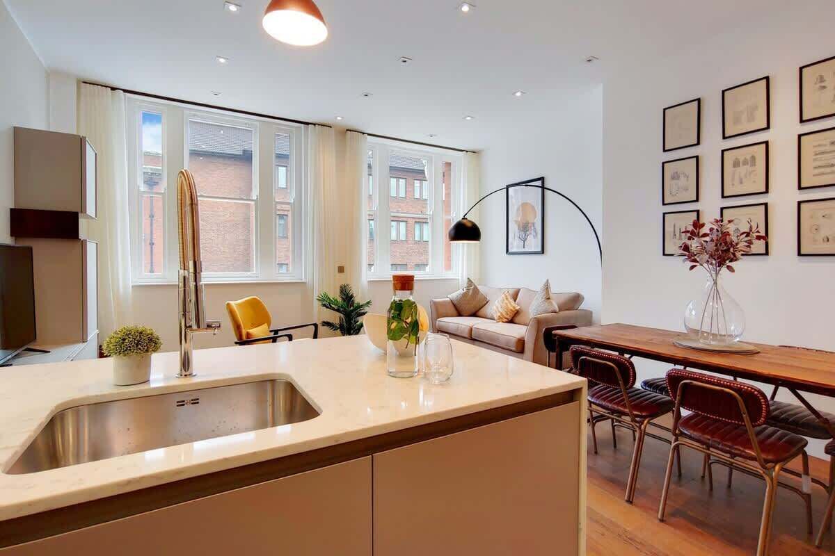 A modern kitchen with a sink, a dining table with chairs, a sofa, and a coffee table.