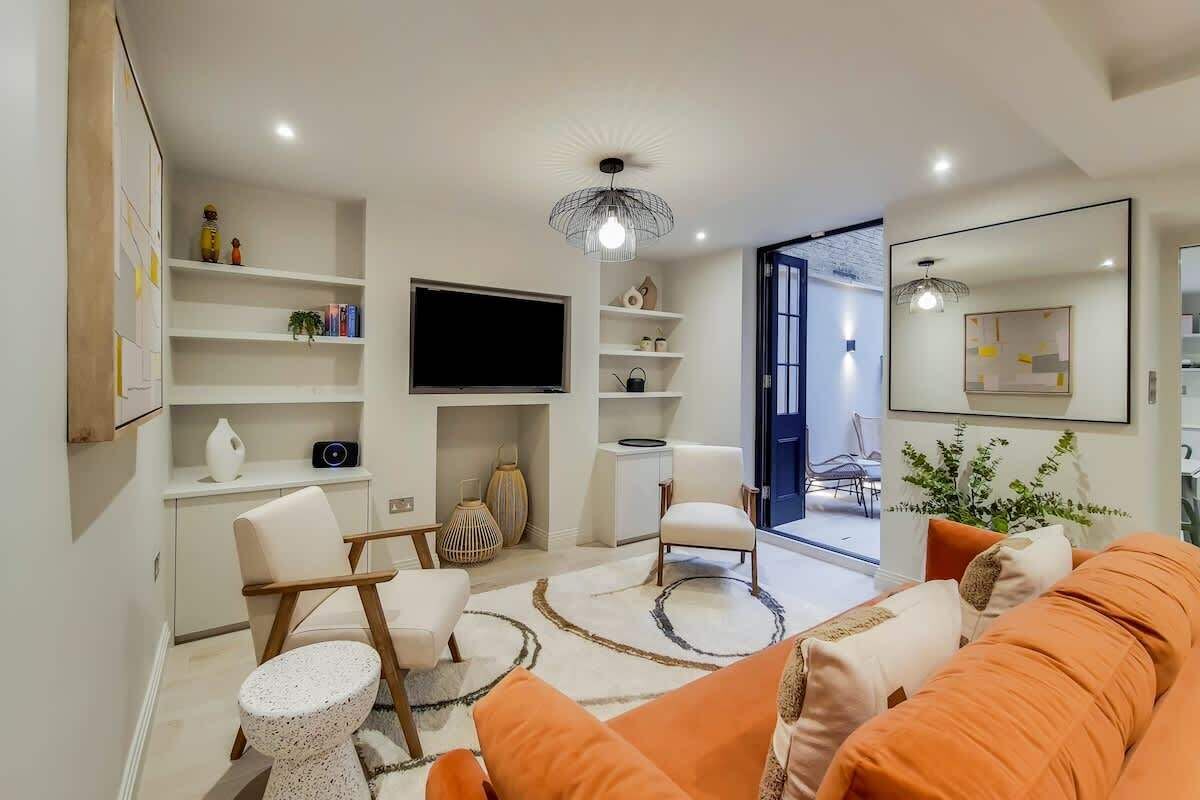 Un salon moderne comprenant un canapé, des fauteuils, un téléviseur, des étagères et un coin repas.