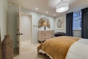 Ein Schlafzimmer mit Bett, Nachttisch, Schminktisch und einem an der Wand befestigten Ventilator.