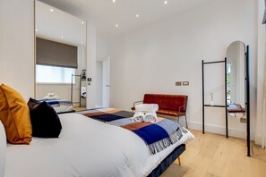 A modern hotel room with a large bed, a red chair, a mirror, and a small table. - BR13 - Elegant 1-Bed near London Bridge (Greater London)