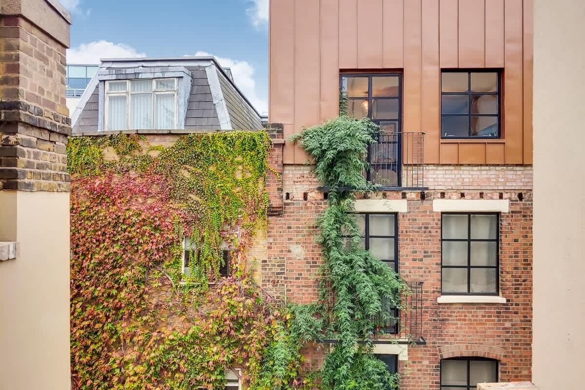 Ein Gebäude mit Ziegelverkleidung, einem Fenster mit Metallgitter und blauem Himmel.